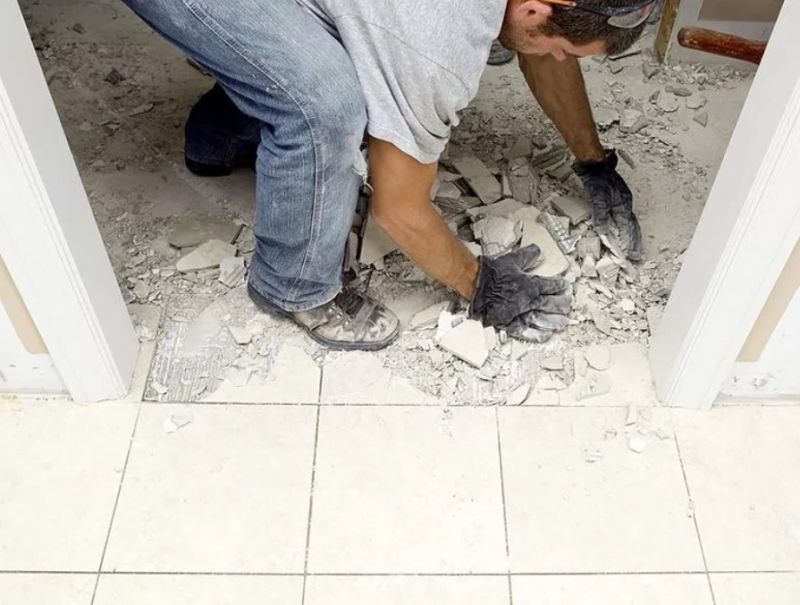 Рабочий демонтирует плитку на полу